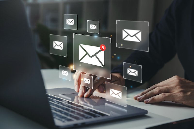 Businessman using laptop with email notification alert on virtual screen.
